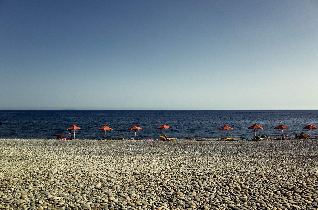 Stony beach and orange umbrellas